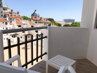 a balcony with a white chair and a view of the city at Vilamoura Marina Apartment with swimming pool in Vilamoura