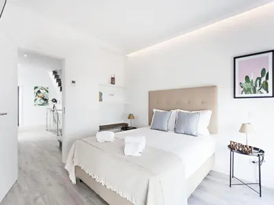 a white bedroom with a large white bed with blue pillows at Faro Clara Suites in Faro