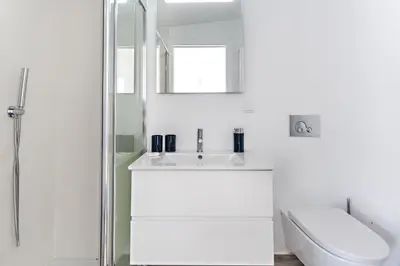 a white bathroom with a sink and a shower at Faro Clara Suites in Faro