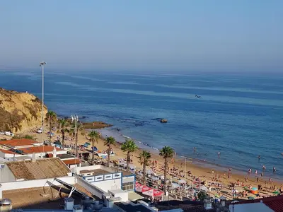 a beach with a lot of people and the ocean at SOMAR Torre de Medronheira OLHOS DE AGUA ALBUFEIRA in Olhos de Água