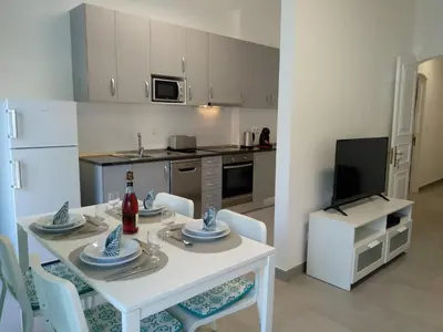a kitchen with a white table with chairs and a white refrigerator at Lote 1 Aconchegante in Quarteira