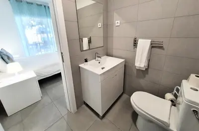 a white bathroom with a sink and a toilet at Lote 1 Aconchegante in Quarteira