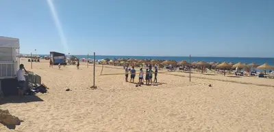 a group of people standing on a beach with umbrellas at T2 Gaveto- Frente Mar, Wifi, Aconchegante & Familiar in Quarteira