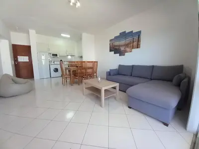 a living room with a blue couch and a table at T2 Gaveto- Frente Mar, Wifi, Aconchegante & Familiar in Quarteira