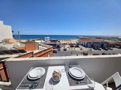 a table on a balcony with a view of the beach at T2 Gaveto- Frente Mar, Wifi, Aconchegante & Familiar in Quarteira