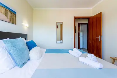 a bedroom with a white bed with towels on it at #005 Foxy B by Home Holidays in Albufeira