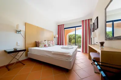 a hotel room with a bed and a desk and windows at AL - Apartamento Vila Sol F5 AH in Quarteira