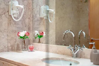 a bathroom with a sink and a mirror and flowers at AL - Apartamento Vila Sol F5 AH in Quarteira