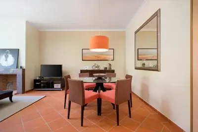 a dining room with a table and chairs and a tv at AL - Apartamento Vila Sol F5 AH in Quarteira