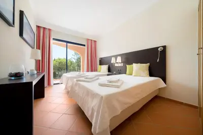a hotel room with two beds and a window at AL - Apartamento Vila Sol F5 AH in Quarteira