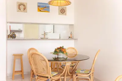 a dining room with a table and chairs at O Apartamento A Ramos Palmeira Galé Está inserido num Condomínio com PISCINA, Fica apenas a 250 Metros da Praia da Galé - Apartamento com Ar Condicionado na Sala, Smart TV com Prime Vídeo e Cozinha Completa in Albufeira