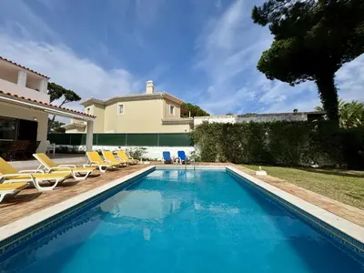 a swimming pool with a table and a yellow umbrella at Vilamoura Ocean Villa with Pool by Homing in Vilamoura