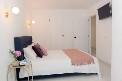 a bedroom with a bed with white walls and a table at Casa Olga Vieira in Albufeira