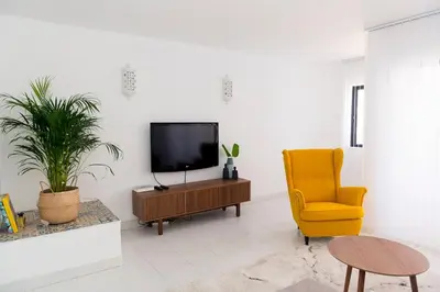 a living room with a tv and a yellow chair at Casa Olga Vieira in Albufeira