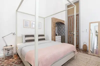 a white bedroom with a canopy bed and a mirror at aleixomor'Aqui in Loulé