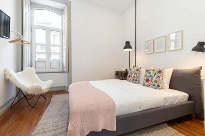 a bedroom with a bed and a chair and a window at aleixomor'Aqui in Loulé