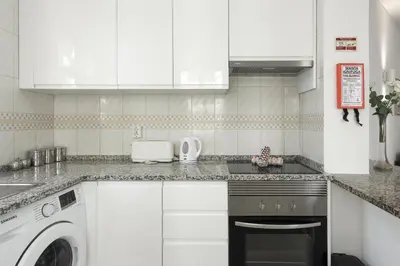 a kitchen with white cabinets and a washer and dryer at Algamar Apartment - Vilamoura Center in Vilamoura