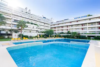 a swimming pool in front of a large building at Apartamento dentro da Marina de Vilamoura in Vilamoura