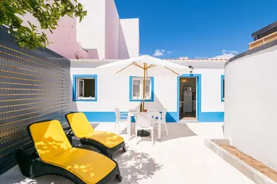 a patio with chairs and an umbrella and a table at LovelyStay - Sweet Escape II - Backyard in Quarteira