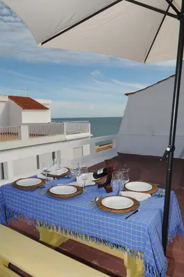 a table with plates and glasses and an umbrella at Rossio in Albufeira