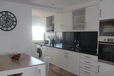 a kitchen with white cabinets and a wooden table at Casa do Largo in Faro