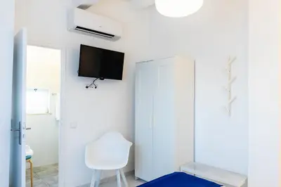 a white room with a white chair and a tv on the wall at Faro Guest House in Faro