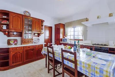 a kitchen with a table with chairs and a kitchen with wooden cabinets at Villa Antao in Guia