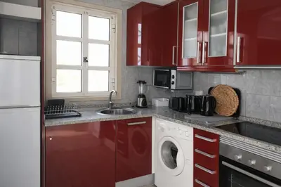 a kitchen with red cabinets and a washing machine at Stylish Center Apartment Vilamoura in Vilamoura
