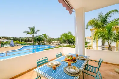 a table and chairs on a balcony with a view of a pool at Villa Isabella in Albufeira