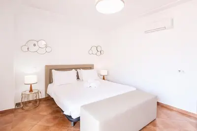 a white bedroom with a white bed and two lamps at Villa Isabella in Albufeira
