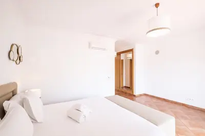 a white bedroom with a large bed with white sheets at Villa Isabella in Albufeira
