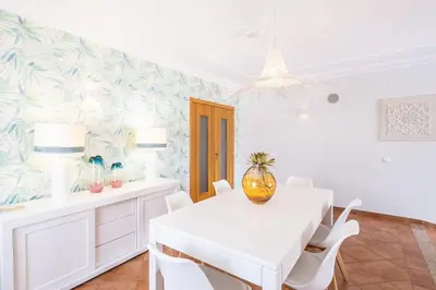 a white dining room with a white table and chairs at Villa Isabella in Albufeira