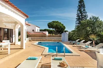 a villa with a swimming pool in front of a house at Spacious 4 bedroom villa, private pool, free air conditioning and wifi in Quarteira