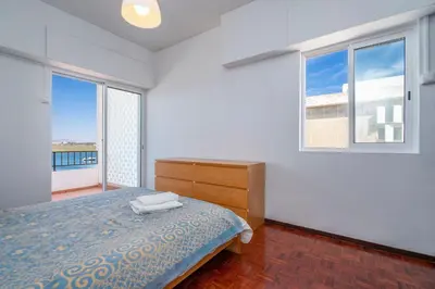 a white bedroom with a bed and a window at Sundance Beach House in Faro