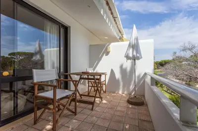 a balcony with a table and chairs and an umbrella at 1Bed Apart Quinta do Lago in Almancil