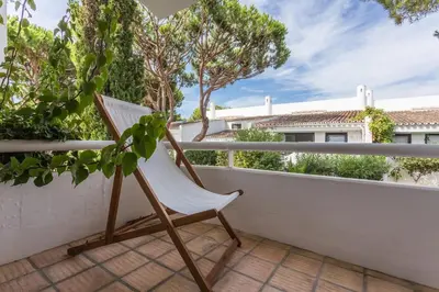 a white chair on a balcony with trees at 1Bed Apart Quinta do Lago in Almancil