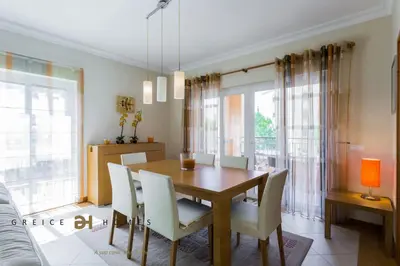 a dining room with a wooden table and white chairs at GREICE HOMES 2 BEDROOM LUXURY APARTMENT VICTORIA BOULEVARD in Vilamoura
