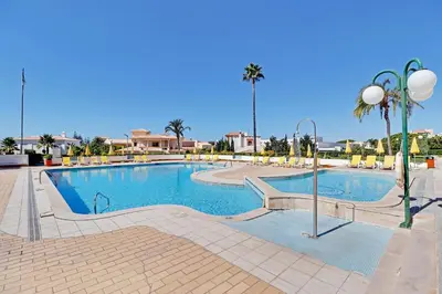 a large swimming pool with chairs and palm trees at Albufeira Concept 1 with Pool by Homing in Guia