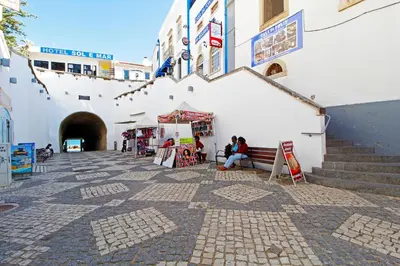 a woman sitting on a bench in front of a building at Albufeira Concept 1 with Pool by Homing in Guia