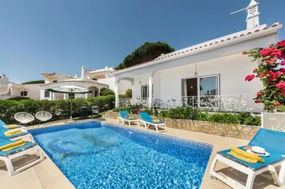a living room with two chairs and a fireplace at Charming Villa With Private Pool in Vibrant Vilamoura, Free AC and Wifi in Quarteira