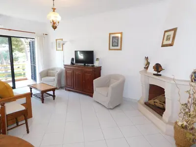 a living room with a tv and two chairs and a coffee table at Sol Nascente Garden in Vilamoura