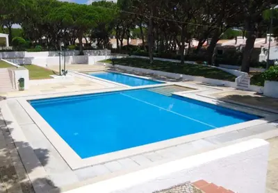 a swimming pool with blue water in a yard at Studio - Praia da Falesia - Algarve in Albufeira