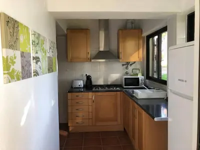 a kitchen with wooden cabinets and a sink and a microwave at Studio - Praia da Falesia - Algarve in Albufeira