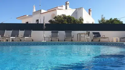 a swimming pool with chairs and a building at AAA Awesome Apartamentos Albufeira in Albufeira