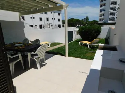 a dining room table with white chairs and a black table at Estrela Mar Marina Villa in Quarteira