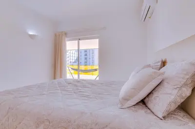 a white bedroom with a bed and a window at Varandas do Sul - Near Vilamoura Marina in Vilamoura