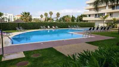 a large swimming pool with chairs and a building at Vilamoura Sun Aquamar 503 in Quarteira