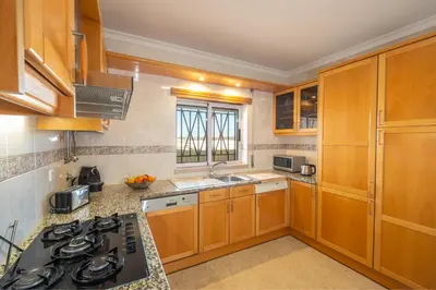 a kitchen with wooden cabinets and a stove top oven at VR Galé Mar in Albufeira