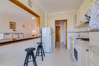 a kitchen with a white refrigerator and two stools at Falésia II - Nice Apartment - Vilamoura in Vilamoura