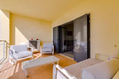 a living room with white furniture and a balcony at Paraísos do Pinhal - 2 Bedrooms - Vilamoura in Vilamoura